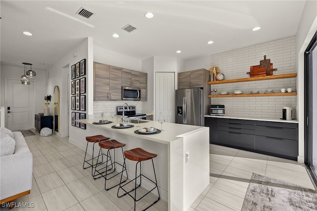 kitchen featuring a breakfast bar, sink, decorative backsplash, appliances with stainless steel finishes, and light tile patterned flooring