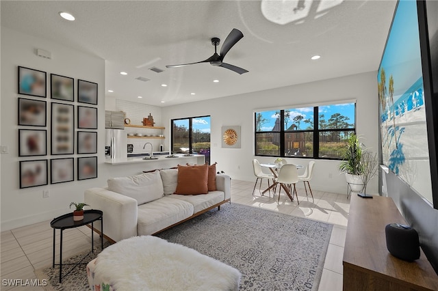 tiled living room featuring ceiling fan, sink, and a textured ceiling