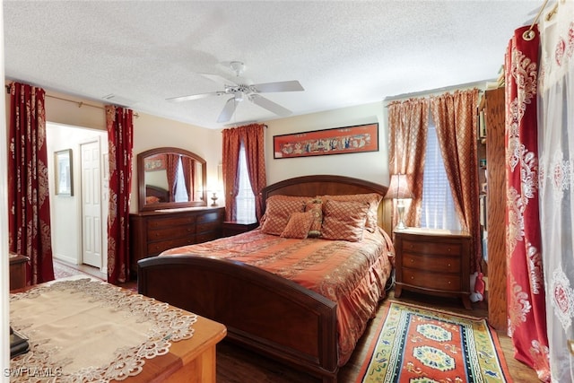 bedroom featuring ceiling fan, hardwood / wood-style floors, and a textured ceiling