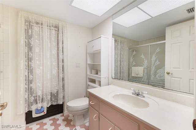 bathroom featuring vanity, toilet, a skylight, and a shower