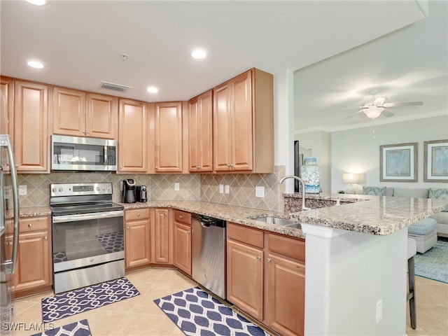 kitchen featuring a kitchen bar, kitchen peninsula, light stone countertops, and appliances with stainless steel finishes