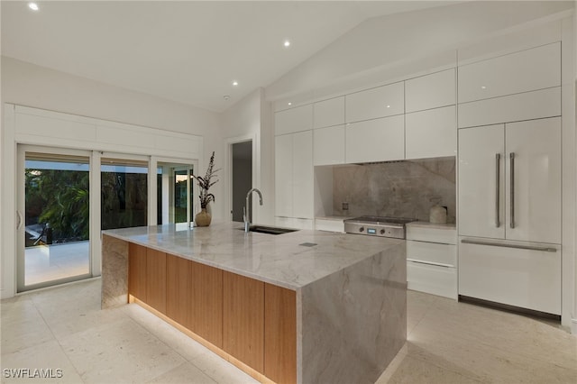 kitchen featuring a spacious island, white cabinetry, lofted ceiling, and sink