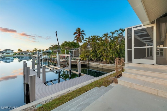 view of dock with a lanai and a water view