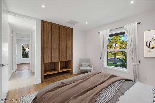 bedroom featuring multiple windows, a closet, and light hardwood / wood-style floors