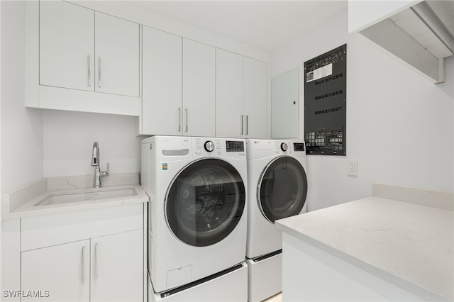 washroom with cabinets, independent washer and dryer, and sink