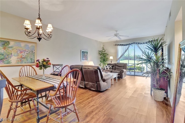 dining room with ceiling fan with notable chandelier and light hardwood / wood-style floors