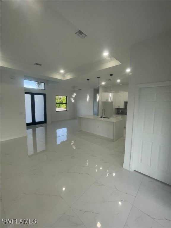 empty room with a tray ceiling, sink, and french doors