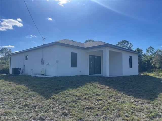 back of house with cooling unit and a yard