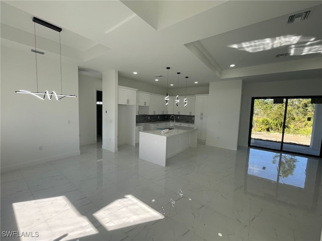 kitchen with sink, white cabinetry, a center island, hanging light fixtures, and a tray ceiling