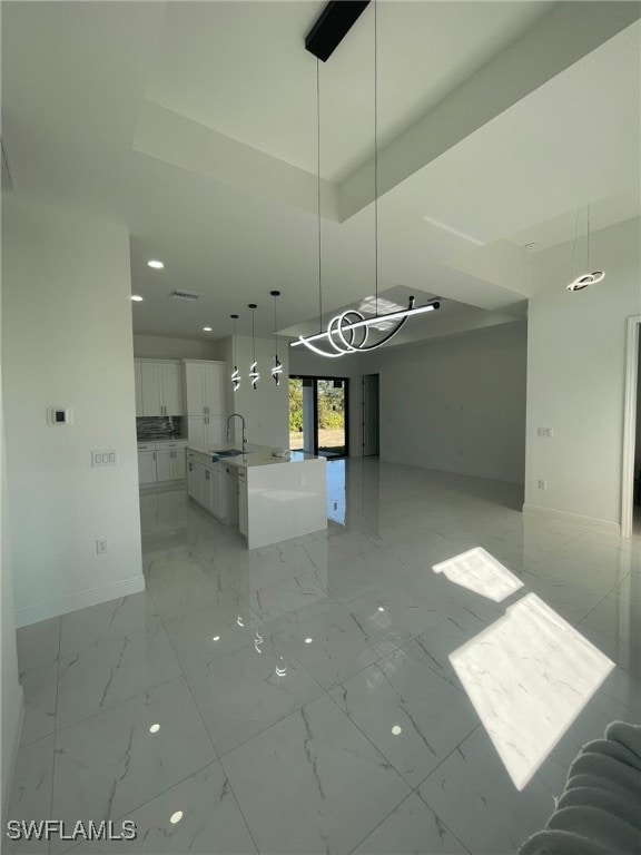 unfurnished dining area featuring sink and a tray ceiling