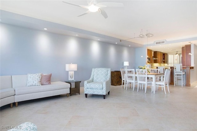 living room featuring light tile patterned floors and ceiling fan with notable chandelier