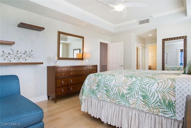 bedroom featuring a raised ceiling, ceiling fan, connected bathroom, light hardwood / wood-style floors, and a closet