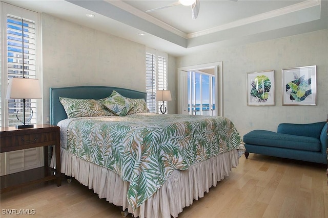 bedroom featuring ceiling fan, wood-type flooring, crown molding, and a tray ceiling