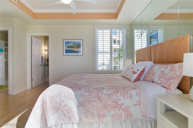 bedroom featuring ornamental molding, a tray ceiling, ceiling fan, and light hardwood / wood-style floors