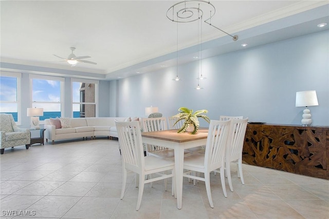 tiled dining space featuring ceiling fan, a water view, and ornamental molding