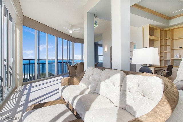 living room featuring ceiling fan, a water view, and ornamental molding