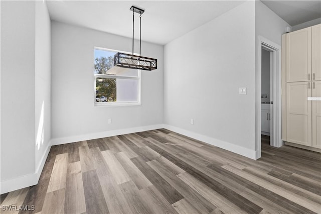 unfurnished dining area featuring wood-type flooring and an inviting chandelier