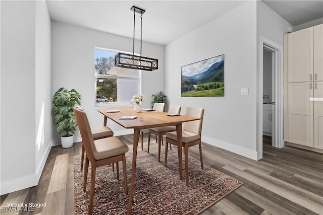 dining room with dark wood-type flooring and an inviting chandelier