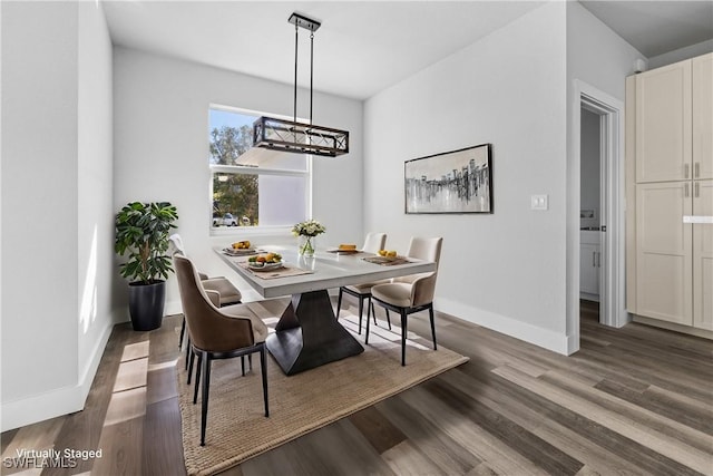 dining space with dark hardwood / wood-style floors and a notable chandelier