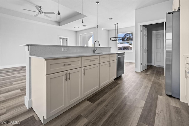 kitchen featuring decorative light fixtures, sink, stainless steel appliances, and a kitchen island with sink