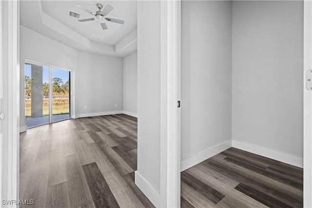 unfurnished room with ceiling fan, dark hardwood / wood-style floors, and a raised ceiling