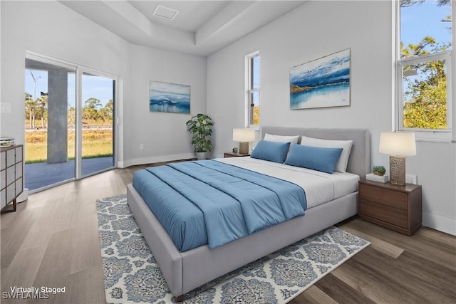 bedroom featuring access to exterior, hardwood / wood-style floors, and multiple windows