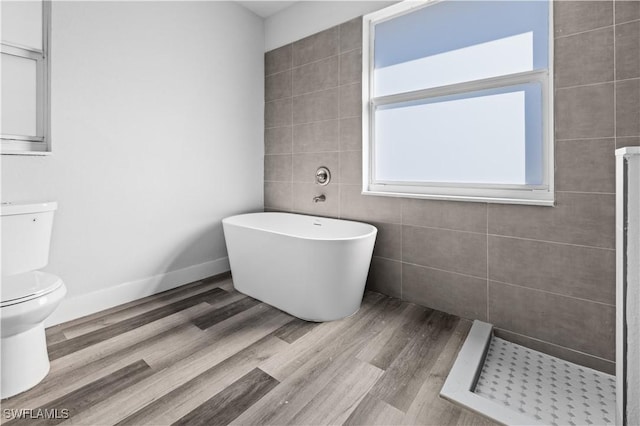 bathroom with wood-type flooring, tile walls, toilet, and separate shower and tub