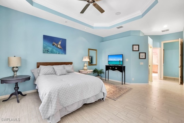 bedroom with ceiling fan, light wood-type flooring, crown molding, and a tray ceiling