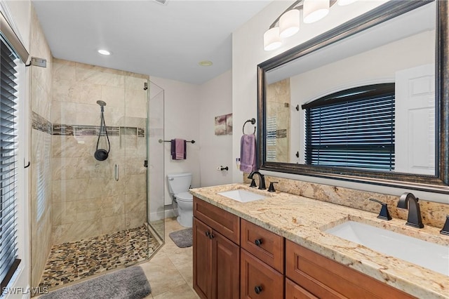 bathroom featuring tile patterned floors, vanity, toilet, and a shower with shower door