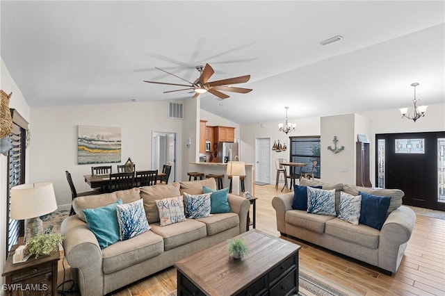 living room featuring ceiling fan with notable chandelier and vaulted ceiling