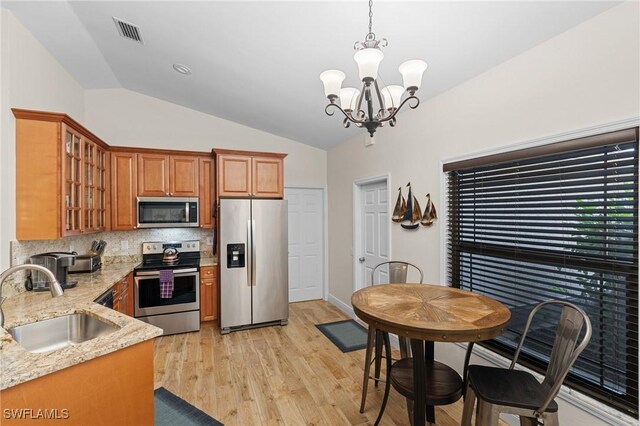 kitchen featuring sink, stainless steel appliances, light stone counters, a notable chandelier, and lofted ceiling