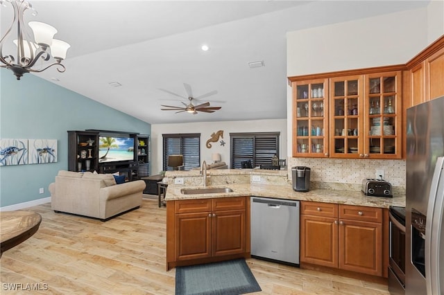 kitchen featuring lofted ceiling, backsplash, sink, kitchen peninsula, and stainless steel appliances