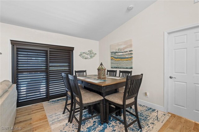 dining space featuring wood-type flooring and vaulted ceiling