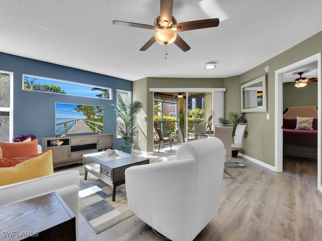 living room with a healthy amount of sunlight, ceiling fan, a textured ceiling, and light wood-type flooring