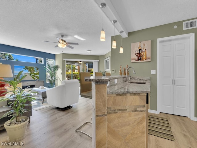 kitchen featuring beam ceiling, light hardwood / wood-style floors, sink, and hanging light fixtures