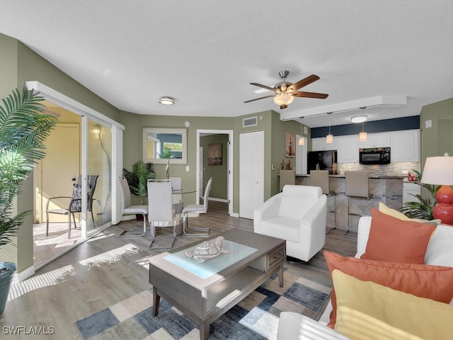 living room with dark hardwood / wood-style floors, a textured ceiling, and ceiling fan