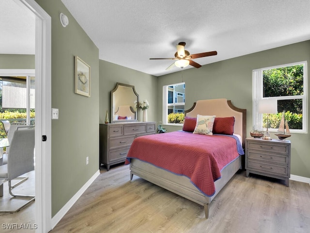 bedroom with a textured ceiling, ceiling fan, and light wood-type flooring