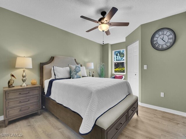 bedroom featuring a textured ceiling, ceiling fan, and light wood-type flooring