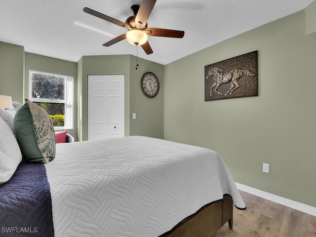 bedroom with hardwood / wood-style floors, a textured ceiling, and ceiling fan