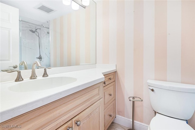 bathroom featuring vanity, toilet, and a tile shower