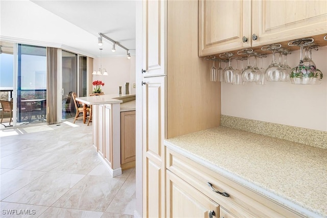 kitchen with light brown cabinetry, decorative light fixtures, and track lighting