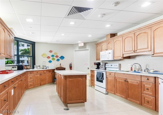 kitchen with a kitchen island, white appliances, sink, and light tile patterned floors