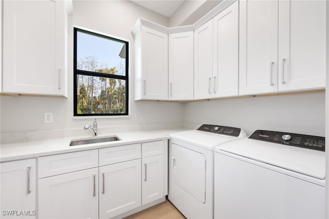 laundry room featuring washing machine and clothes dryer, cabinets, and sink