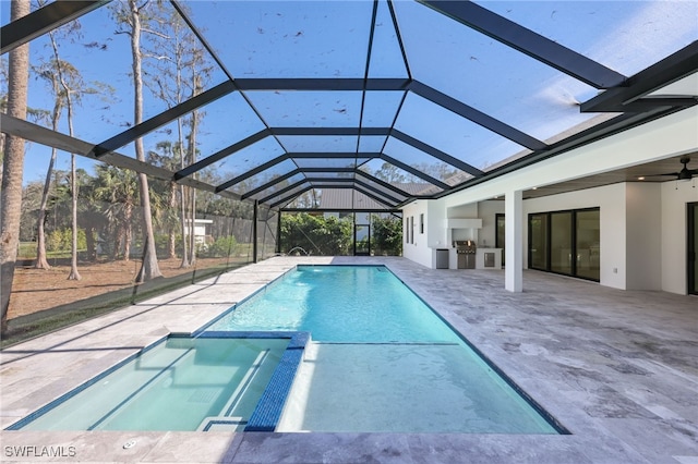 view of swimming pool with a patio, ceiling fan, a lanai, and exterior kitchen