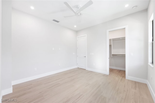 unfurnished bedroom with a closet, ceiling fan, light hardwood / wood-style flooring, and a walk in closet