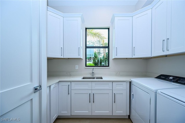 washroom with cabinets, washing machine and dryer, and sink