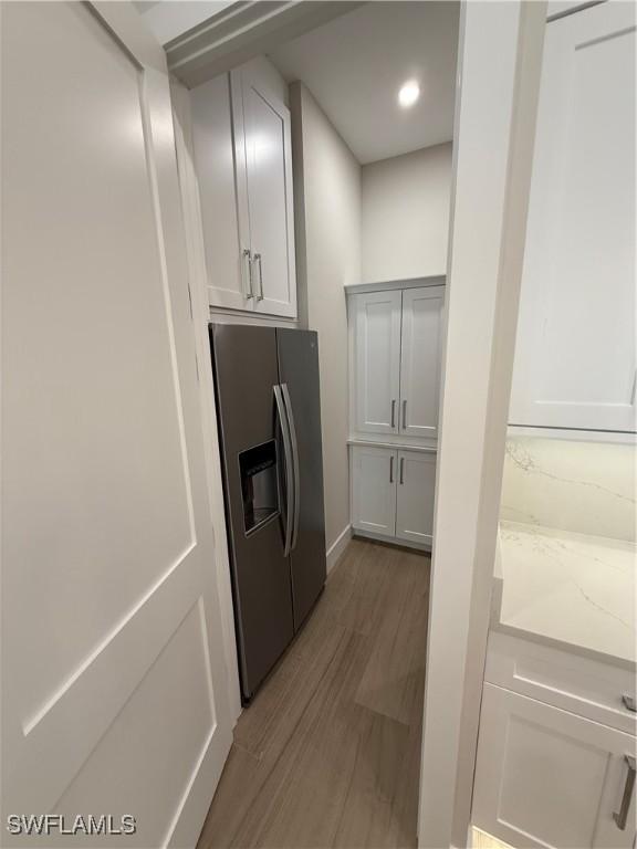 kitchen featuring white cabinets, wood-type flooring, and stainless steel refrigerator with ice dispenser