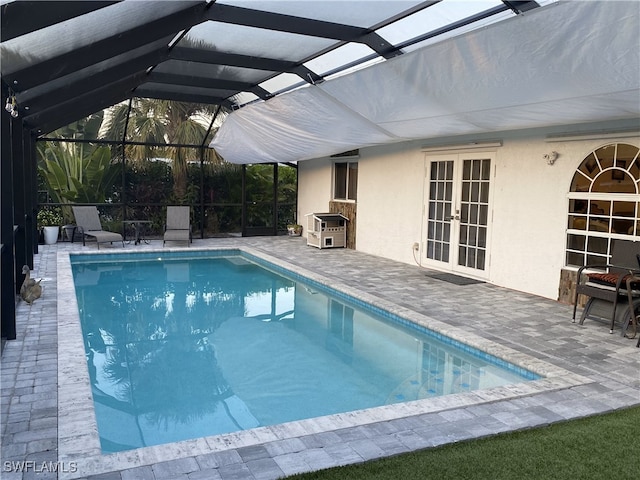 pool featuring glass enclosure, french doors, and a patio