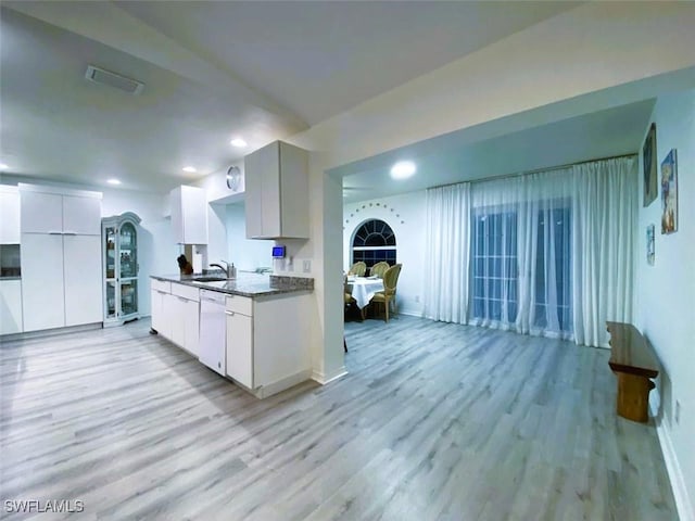 kitchen with white dishwasher, sink, white cabinets, and light wood-type flooring