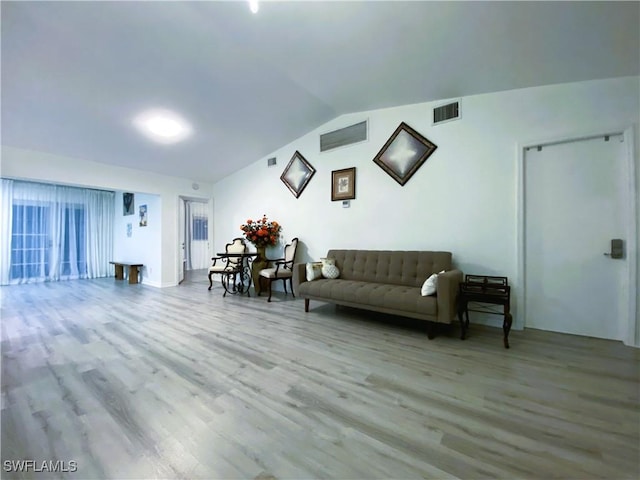 living room featuring lofted ceiling, wood finished floors, and visible vents